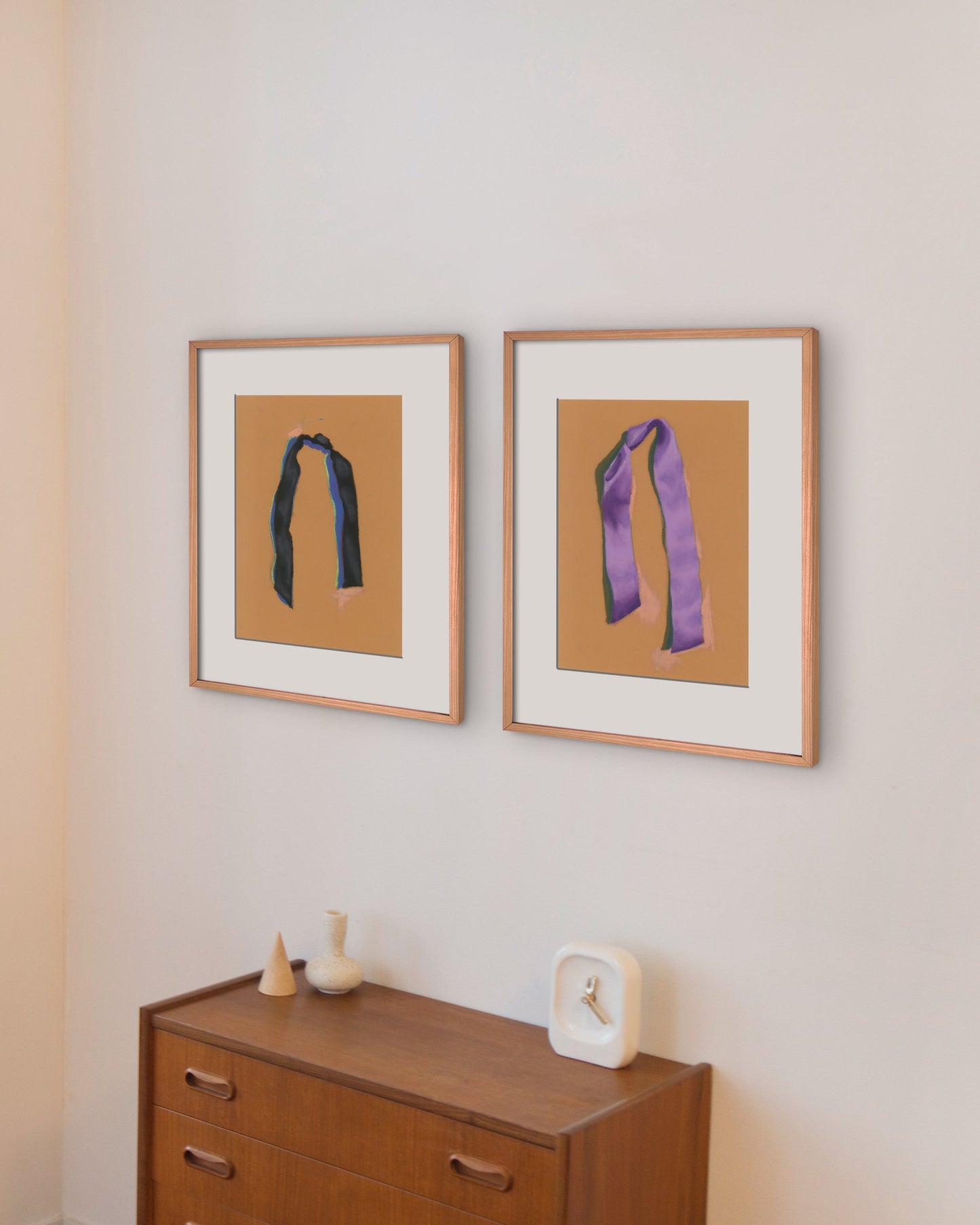 Two framed artworks on a wall with a wooden side table.