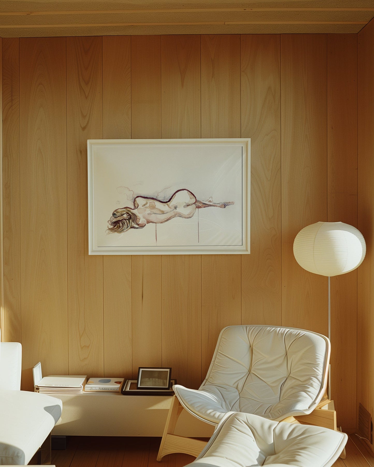A watercolor painting featuring a nude minimalist figure hanging on a warm wood-paneled wall in a design-focued, sunlit living room with a mid-century white armchair and floor lamp.