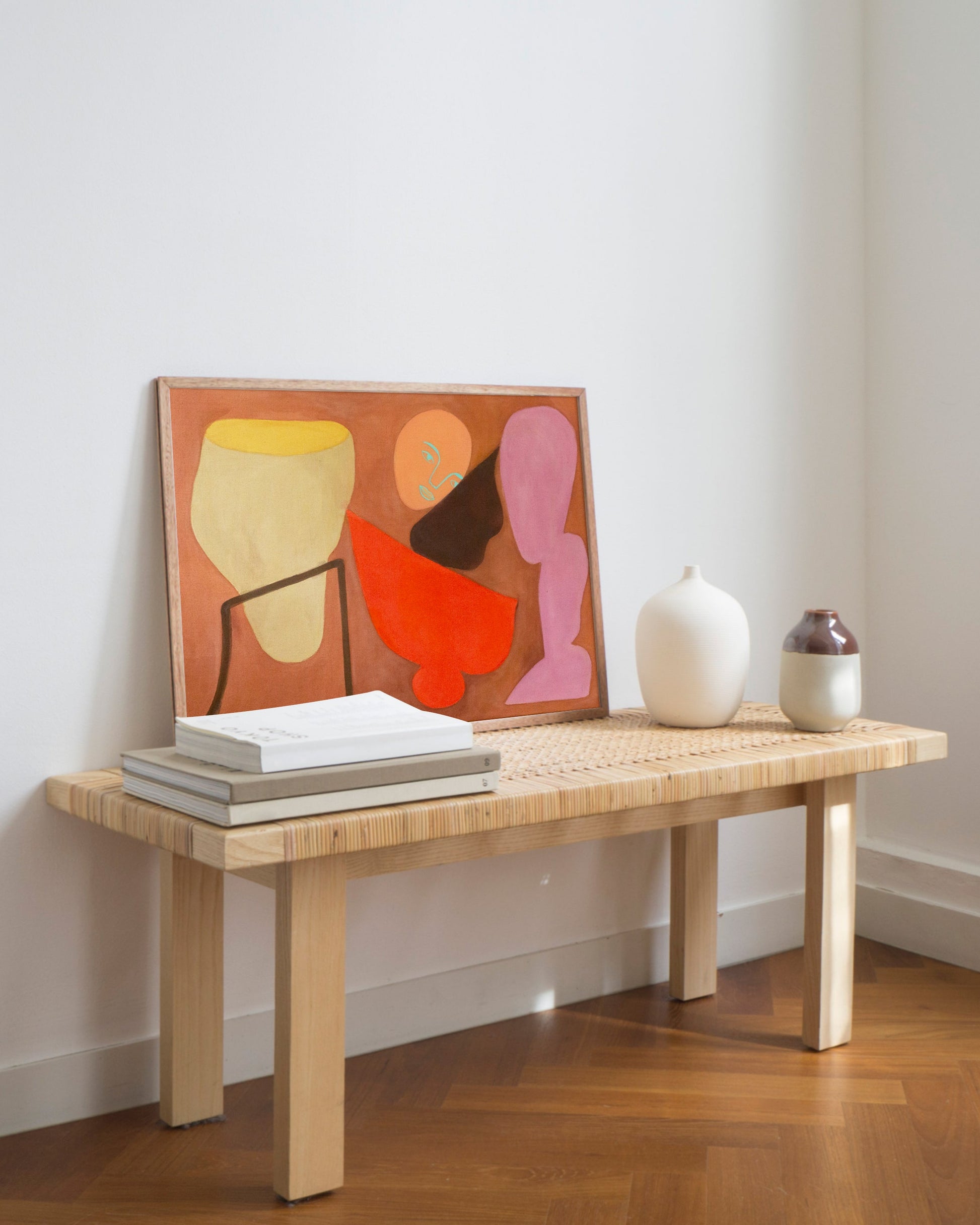 Colorful abstract painting on a wooden bench leaning against a white wall.
