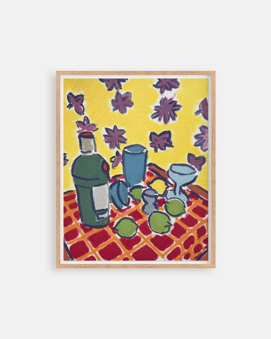 Framed artwork of a still life scene with bottles and fruit on a checkered tablecloth against a yellow background.