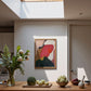 Modern kitchen with wooden table, plants, and abstract art on the wall.