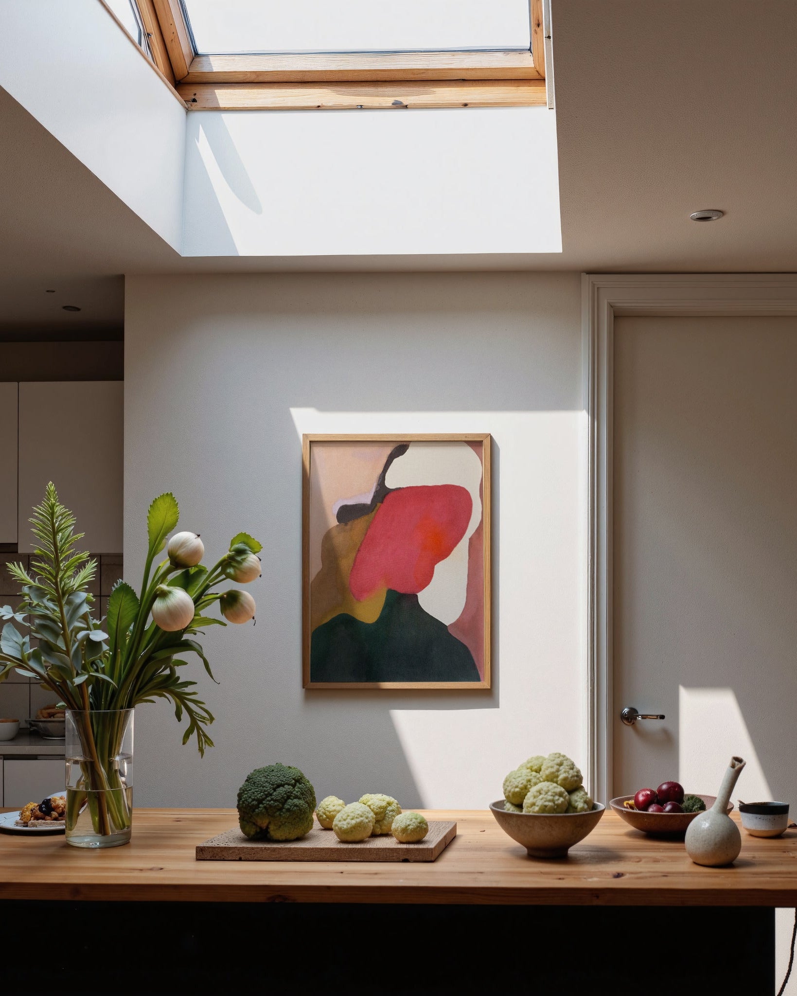 Modern kitchen with wooden table, plants, and abstract art on the wall.