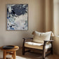 Modern interior with a wooden chair, small table, and abstract painting on a beige wall.