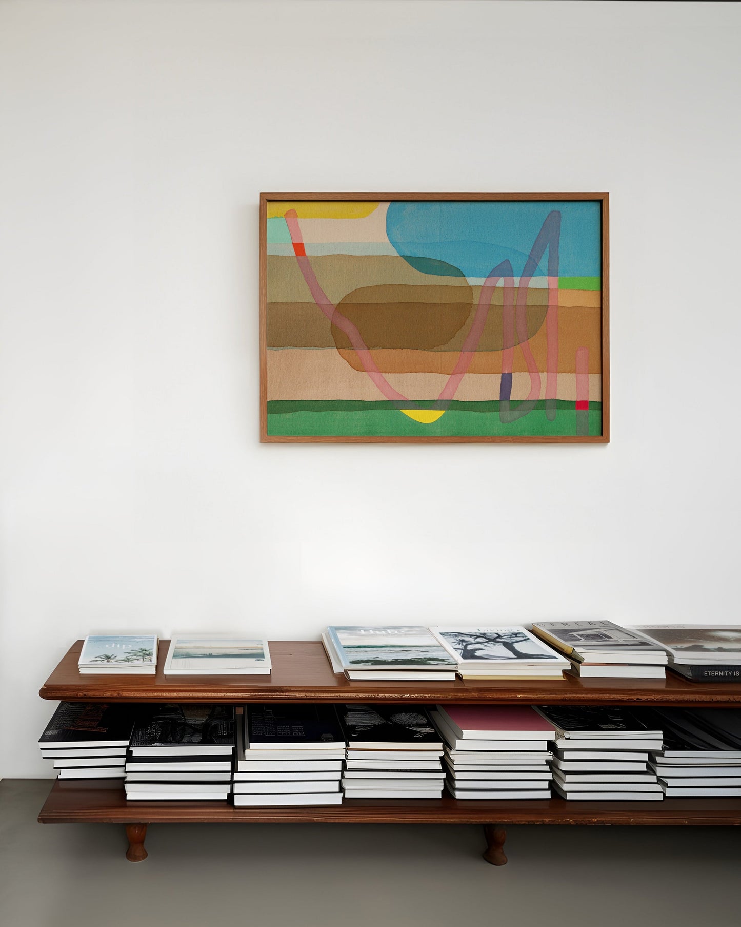 Modern interior with a wooden bookcase and a colorful abstract painting on the wall.