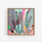 Abstract artwork with colorful shapes in a wooden frame on a white wall.