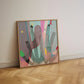 Colorful abstract artwork in a wooden frame leaning on a white wall with a herringbone wooden floor.
