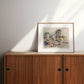 Framed still life artwork on a wooden cabinet 