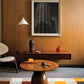 Modern living room with wooden table, chair, and black and white photograph on the wall.