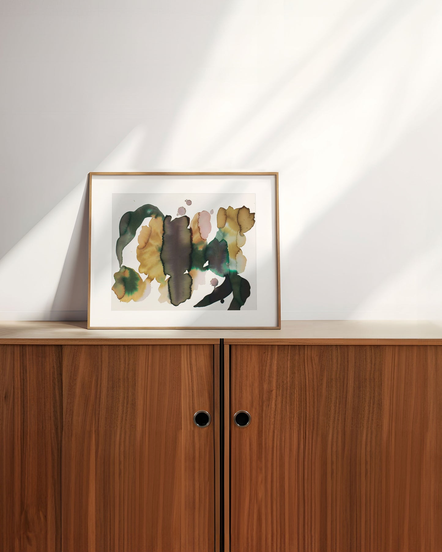 Framed abstract artwork on a wooden cabinet.