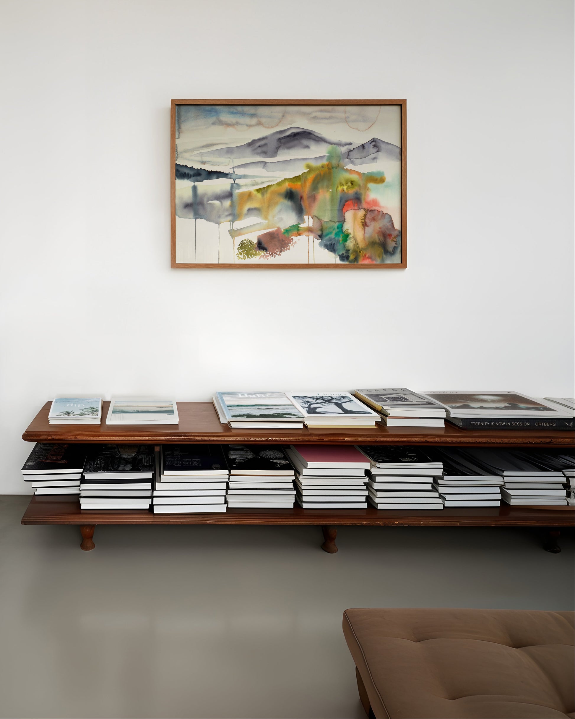 Living room with framed colorful abstract landscape painting on a white wall.
