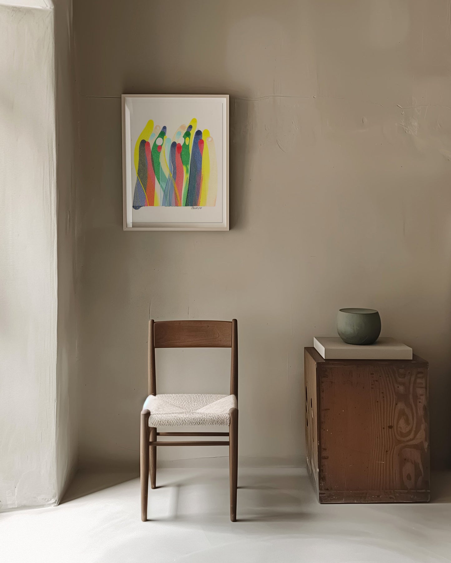 Colorful abstract painting on a beige wall in a minimalist room. with a chair and side table.