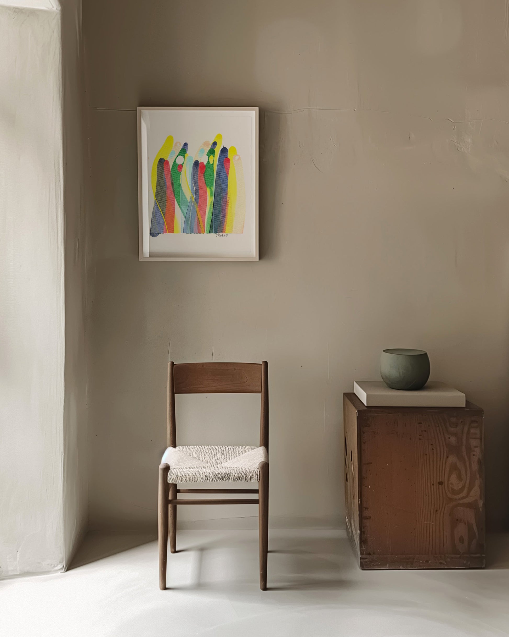 Colorful abstract painting on a beige wall in a minimalist room. with a chair and side table.