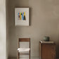 Minimalist room with a wooden chair, small table, and framed artwork.