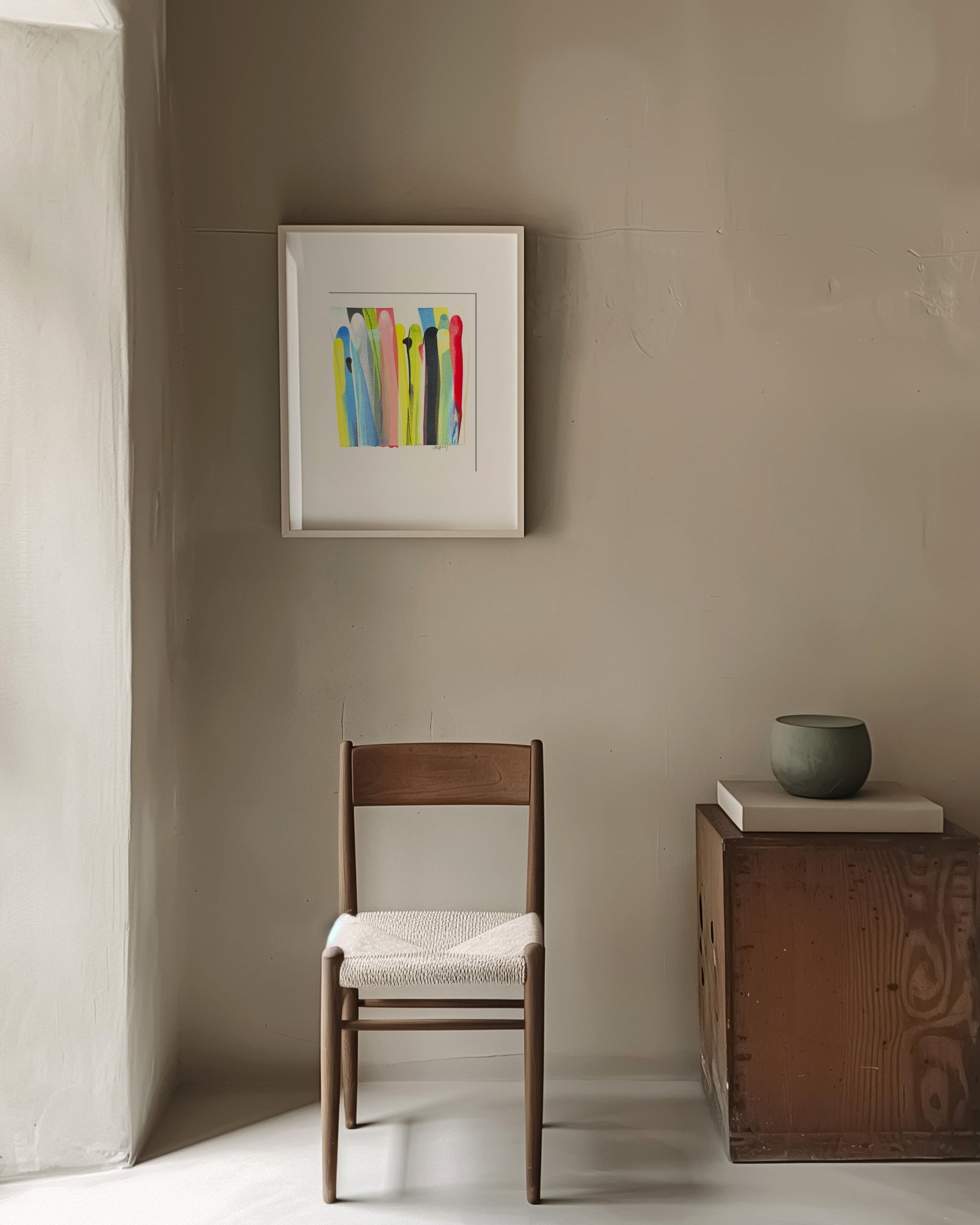 Minimalist room with a wooden chair, small table, and framed artwork on a beige wall.